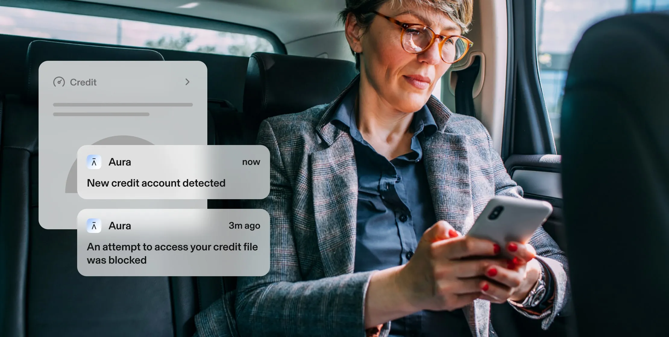 Woman in a car receives 2 credit alerts from Aura on phone. Alerts: New credit account detected, and An attempt to access your credit file was blocked.